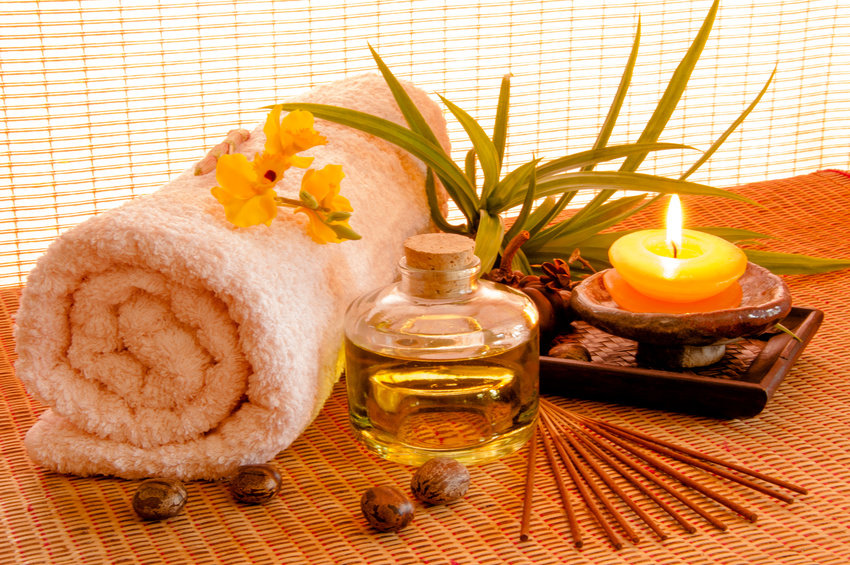 Essential oil bottles, towels, candle and flower in health spa for spa treatment.
